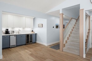 Een moderne keuken met witte kastjes, een vaatwasser en een trap naar een ander niveau.