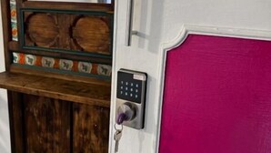 Una puerta con cerradura electrónica, un espejo y un panel de madera con detalles decorativos.