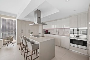 A modern kitchen with a central island, stainless steel appliances, and a large window with a city view. - Ocean front PH stunning views. Luxury Spacious 4-bedroom (Hollywood)