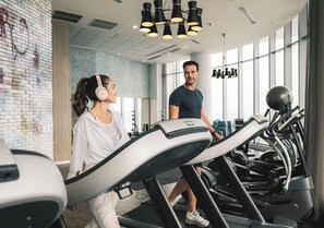 A gym with treadmills, a brick wall, and a large window. - Ocean front PH stunning views. Luxury Spacious 4-bedroom (Hollywood)