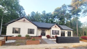 Een gebouw met twee verdiepingen, kenmerkt zich door een strak, modern ontwerp, een plat dak, grote ramen en een voortuin.