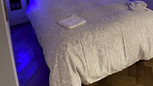 Un dormitorio con una cama grande, cabecera de madera y tragaluz.