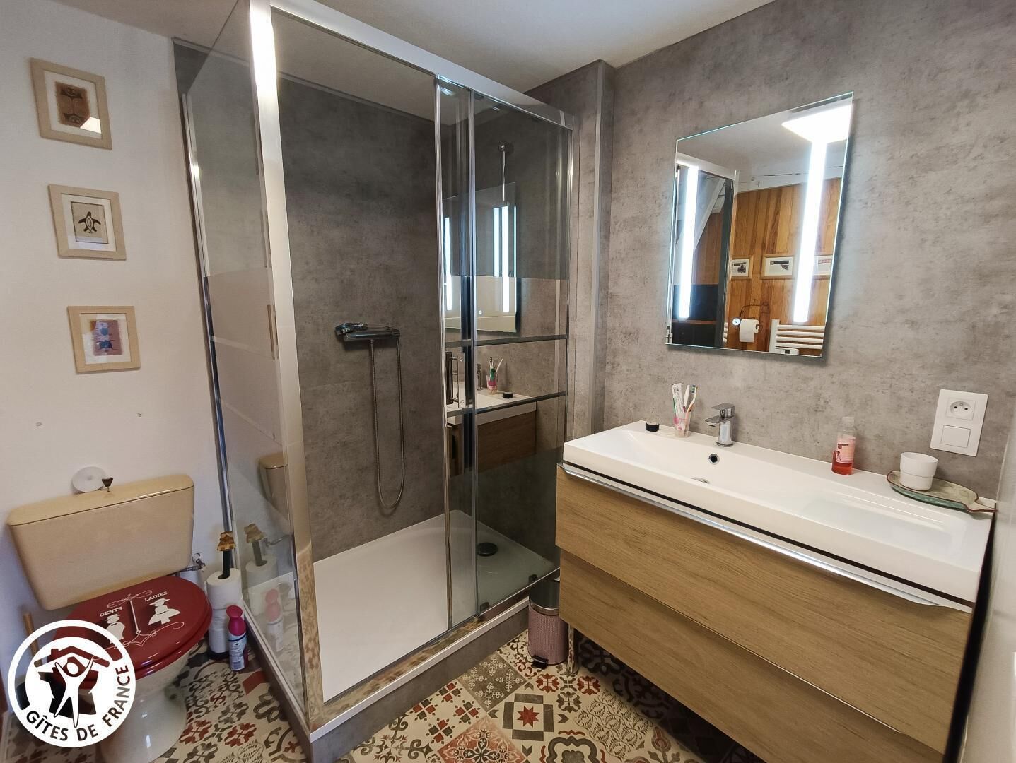 A modern bathroom with a glass-enclosed shower, a white sink with a wooden vanity, and a mirror above the sink.