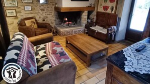 Una sala de estar acogedora con chimenea, sofás de cuero, una mesa de centro y cuadros en las paredes.