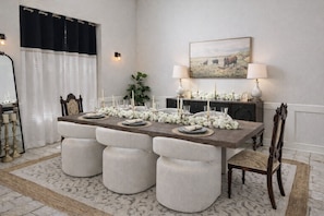 A dining room with a long table, white upholstered chairs, and a chandelier. - Private Resort Pool Home: 2 Suites, Hot Tub, Golf Simulator, Sauna and more (Harrisonville)