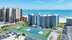A multi-story hotel with a tennis court, parking, and a view of the beach. - Stunning Oceanfront 3-Bedroom, 2-Bath Condo – Breathtaking Views! (New Smyrna Beach)