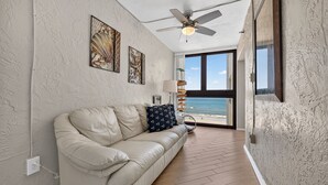 Una stanza con un divano in pelle color beige, una ventola a soffitto e opere d'arte alle pareti.