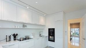 A modern kitchen with white cabinetry, a black oven, and stainless steel appliances.