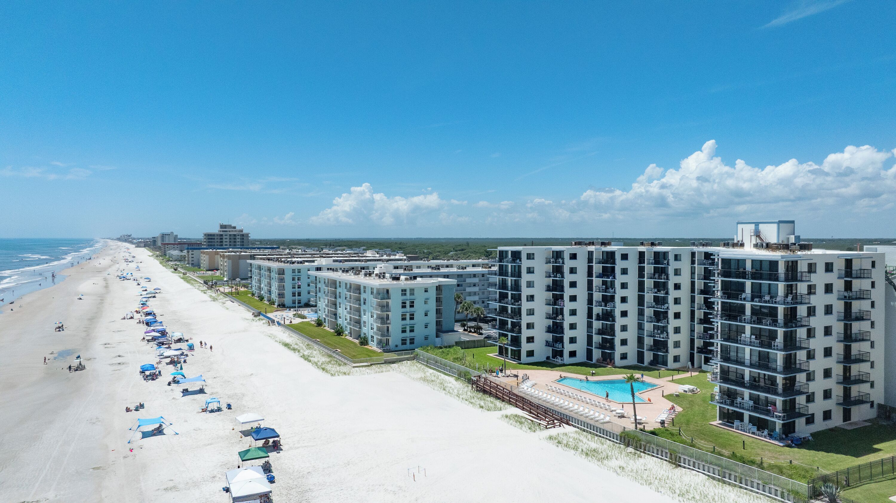 Un hôtel situé en bord de mer, composé de plusieurs immeubles de grande hauteur, doté d’une plage de sable et d’une piscine.