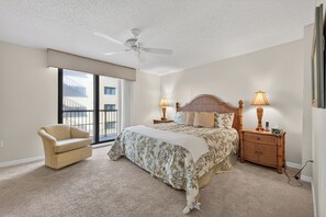 Ein Schlafzimmer mit Bett, Stuhl, Nachttisch, Lampe und Deckenventilator.