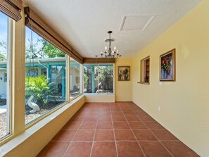 A hallway with a tiled floor, a ceiling fan, and a chandelier. - Beach Access + Community Dock | Coastal Retreat (Englewood)