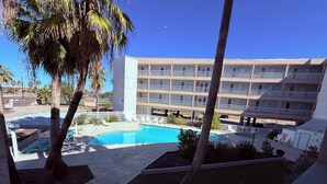 Un hotel con piscina, varios balcones y palmeras.