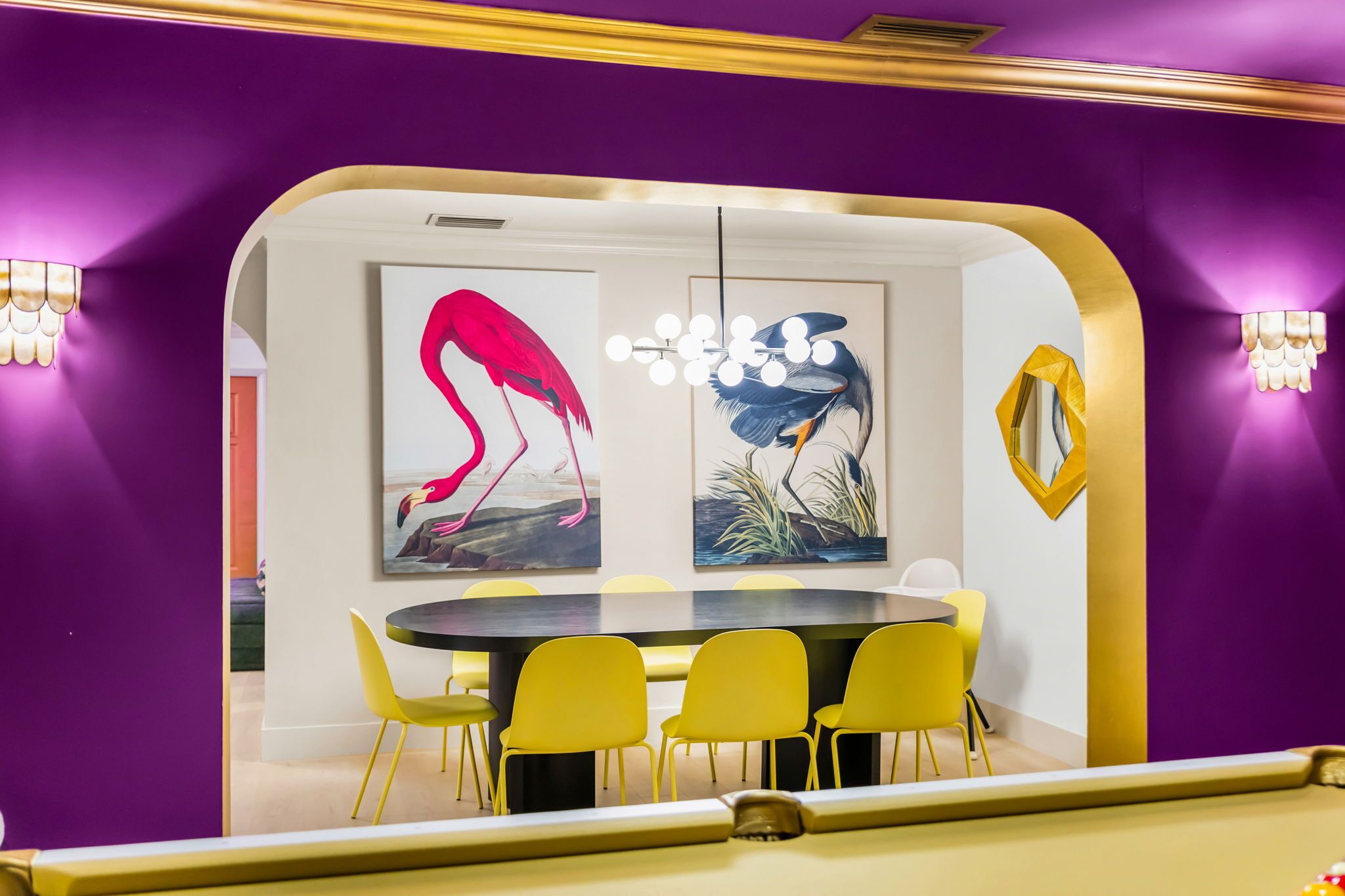 Una sala conferenze con un tavolo rotondo e sedie gialle, circondata da pareti viola e opere d'arte.