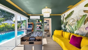 Ein Zimmer mit Blick auf einen Pool, einem Kicker und einem gelben Sofa.