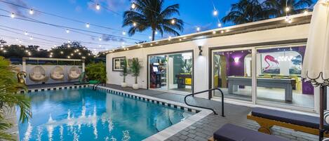 An outdoor swimming pool with lounge chairs and a restaurant area.