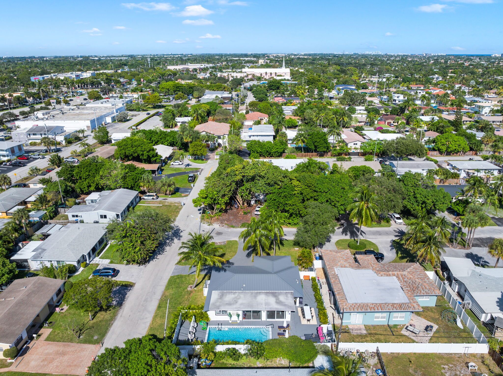 An aerial view of a residential area with houses, a church, and a swimming pool.