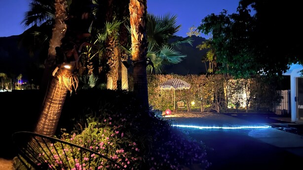 A nighttime outdoor area with a pool, palm trees, and a chair. - Stylish Chic Escape, Private Pool & Golf Course Residence. Fun & Fabulousity (Palm Springs)