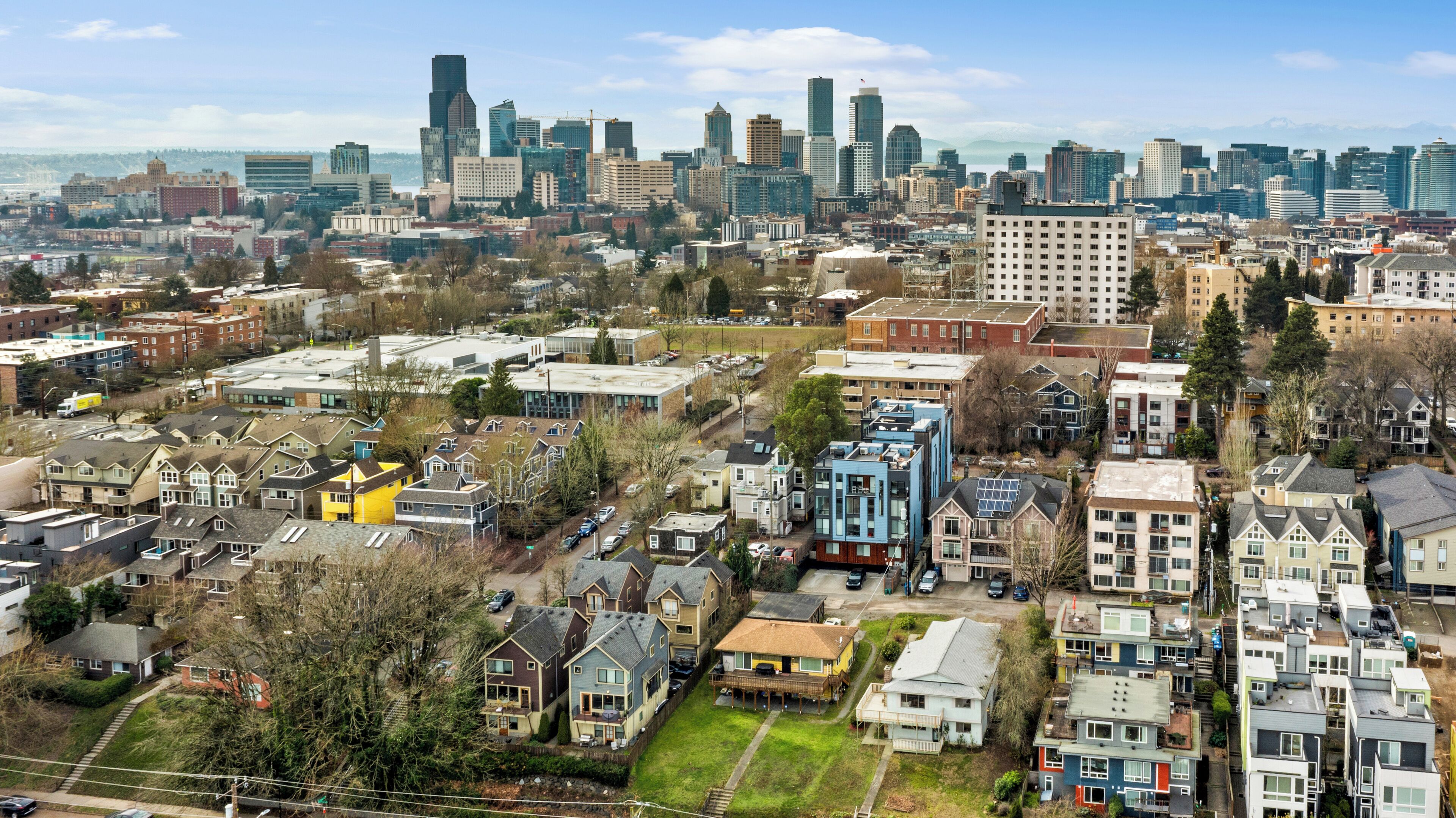 Un quartier résidentiel composé d’un mélange de maisons unifamiliales et d’immeubles d’appartements, entouré d’une vue sur la ville, avec ses gratte-ciel modernes.