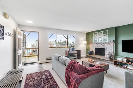 A modern living room with a fireplace, a sofa, a coffee table, and a TV.