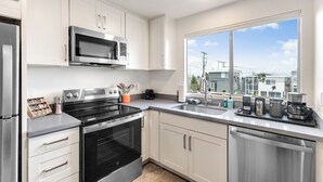 Een moderne keuken met roestvrijstalen apparatuur, witte kasten en een groot raam met uitzicht op de stad.