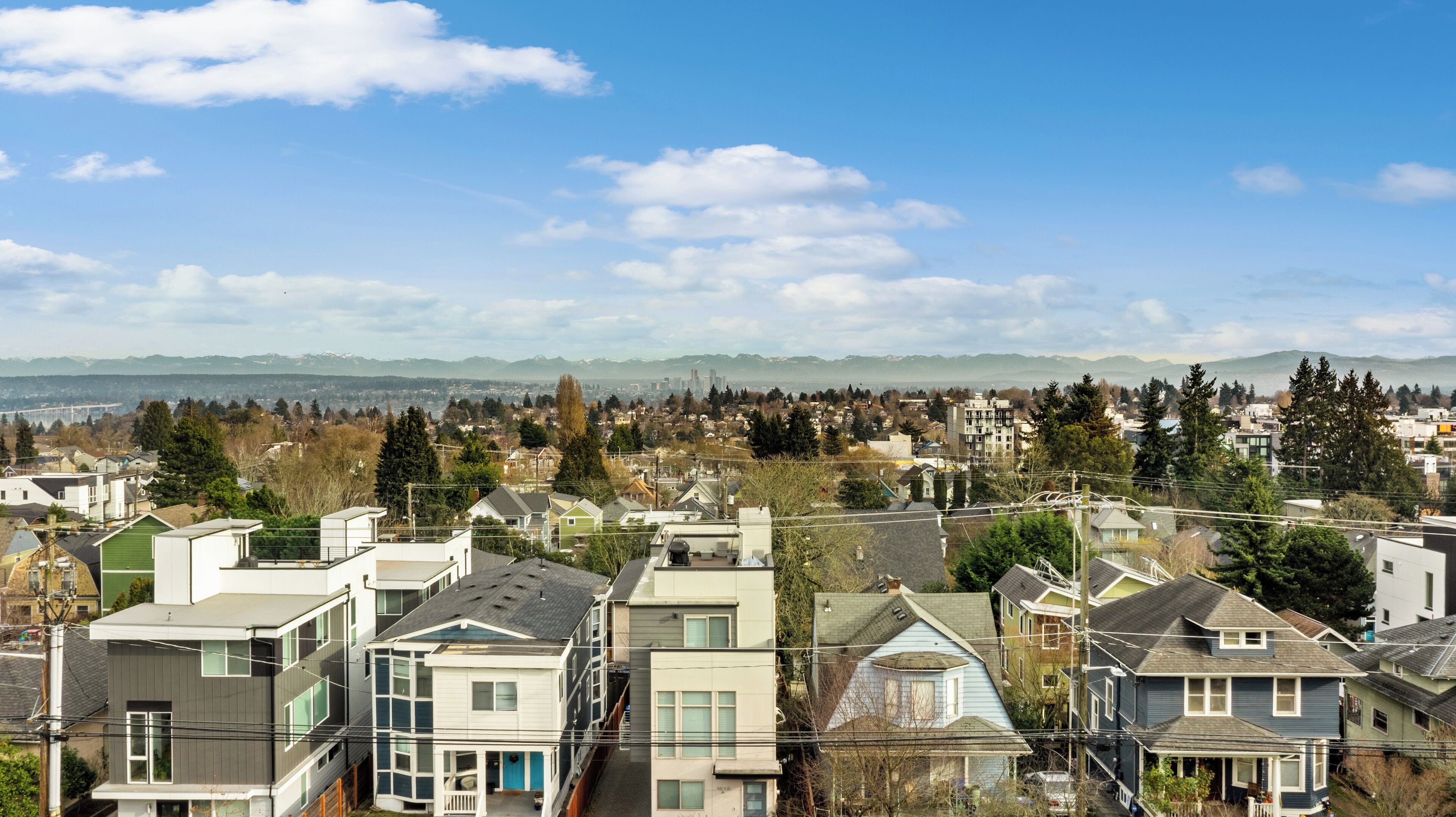 A residential area with modern houses, a clear sky, and distant mountains.
