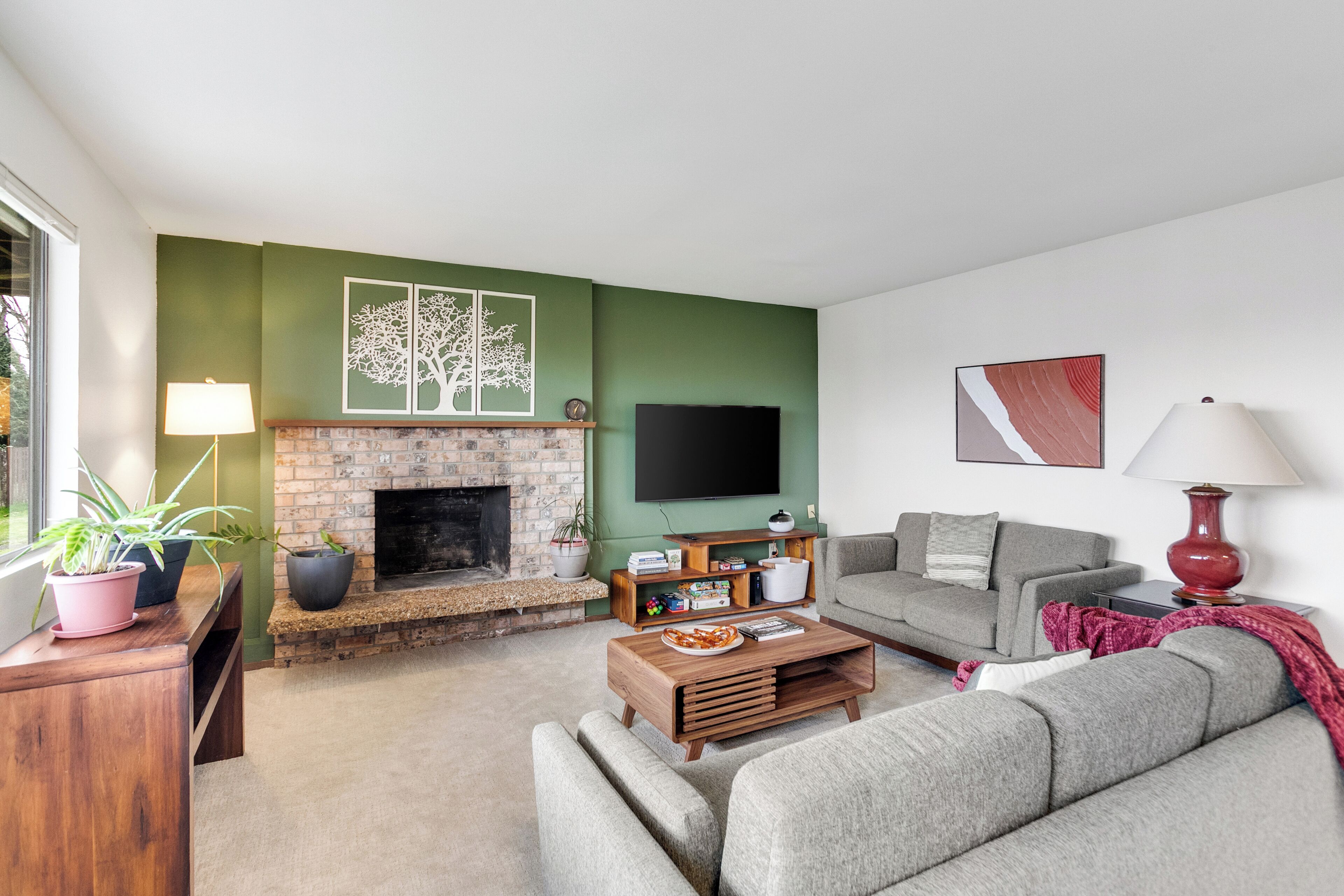 A living room with a fireplace, a flat-screen TV, a grey sofa, and a coffee table.