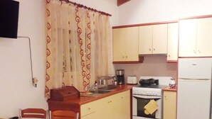 Cocina compacta con zona de comedor, que presenta techo de madera, horno pequeño, refrigerador y mesa de comedor con sillas.