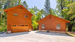 Dos cabañas de madera con garajes adosados, rodeadas de árboles.