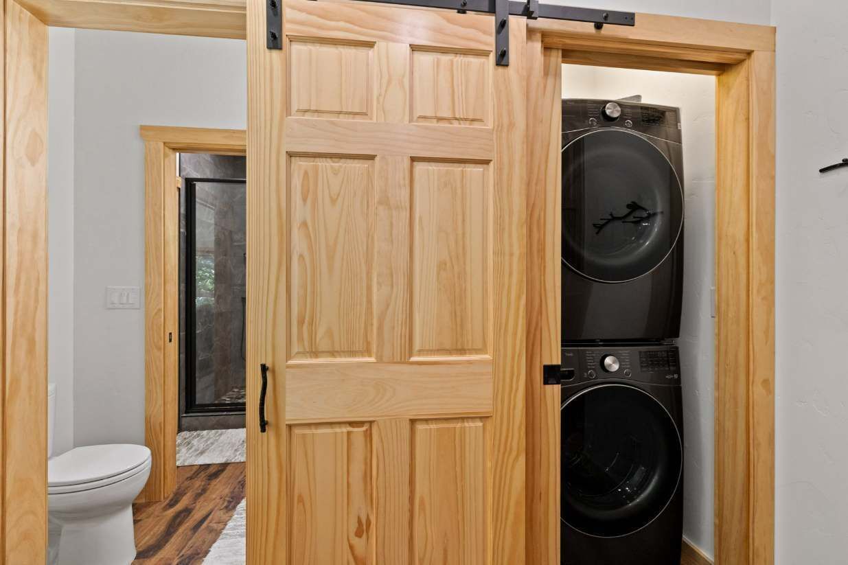 Ein Waschraum mit Holztür, Waschmaschine und Trockner.