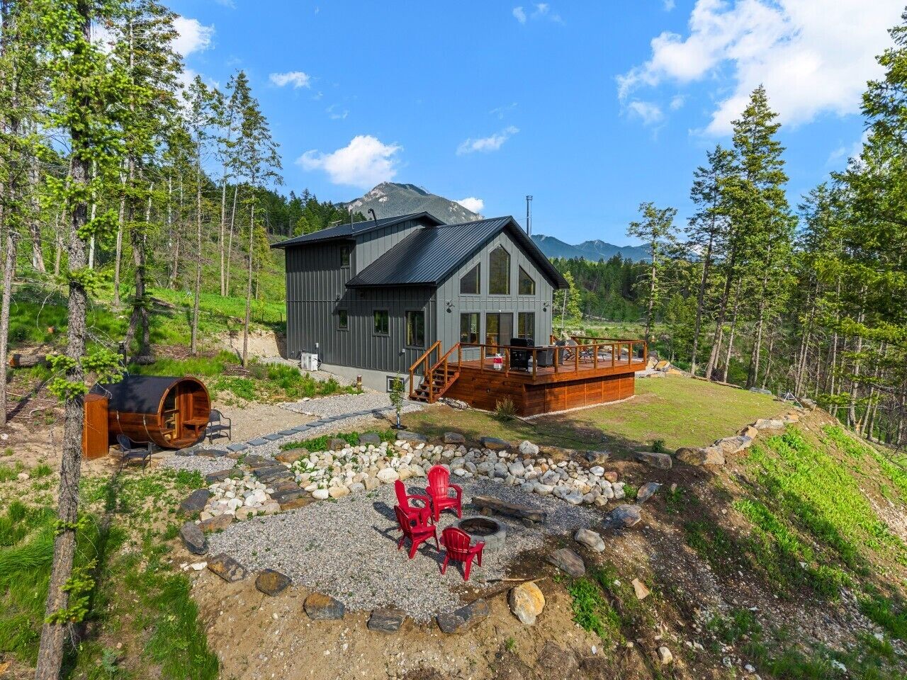 Outdoor view of the house featuring a large deck, fire pit, and barrel sauna.