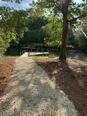 A gravel path leading to a dock over water, surrounded by trees.