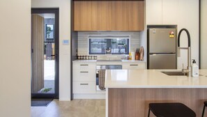 Una cocina moderna con una isla central, electrodomésticos de acero inoxidable y vistas a la calle.