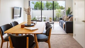 Una sala de estar moderna con comedor, que incluye un ventanal grande, un conjunto de sofás y una mesa de centro.