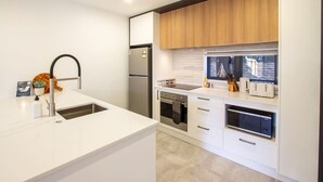 Una cocina moderna con un refrigerador de acero inoxidable, un horno empotrado y una isla grande con un lavamanos.