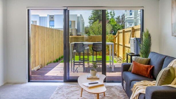 Una sala de estar moderna con un gran ventanal corredero que da a un patio.