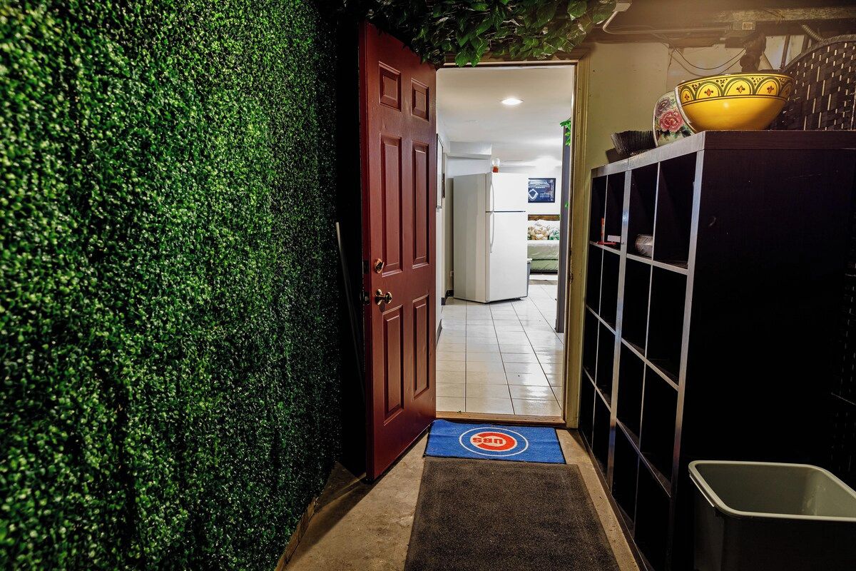 A hallway with a green wall, a red door, and a blue mat leading to a room.