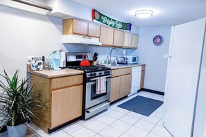 A compact kitchen with wooden cabinets, a gas stove, a microwave, and a coffee maker.