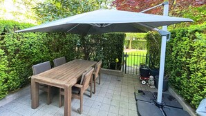 A patio area with a wooden table and chairs, a large umbrella, and a metal chair. - Cozy 2-bedroom townhome in beautiful Vancouver with AC (Vancouver)