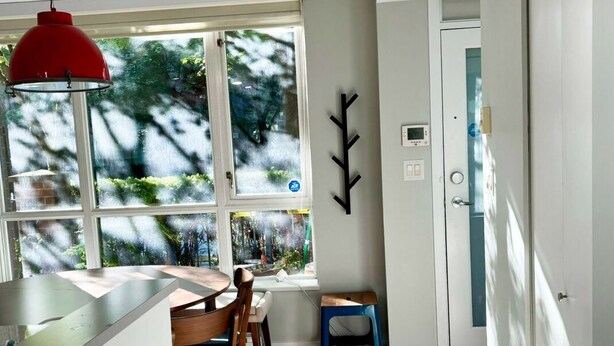 A modern kitchen with a dining area, large windows, and a red pendant light. - Cozy 2-bedroom townhome in beautiful Vancouver with AC (Vancouver)