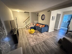 A living room with a blue sofa, a yellow ottoman, and a patterned rug. - Perfect 3-bedroom townhome with AC in nice Charlotte neighborhood (Charlotte)