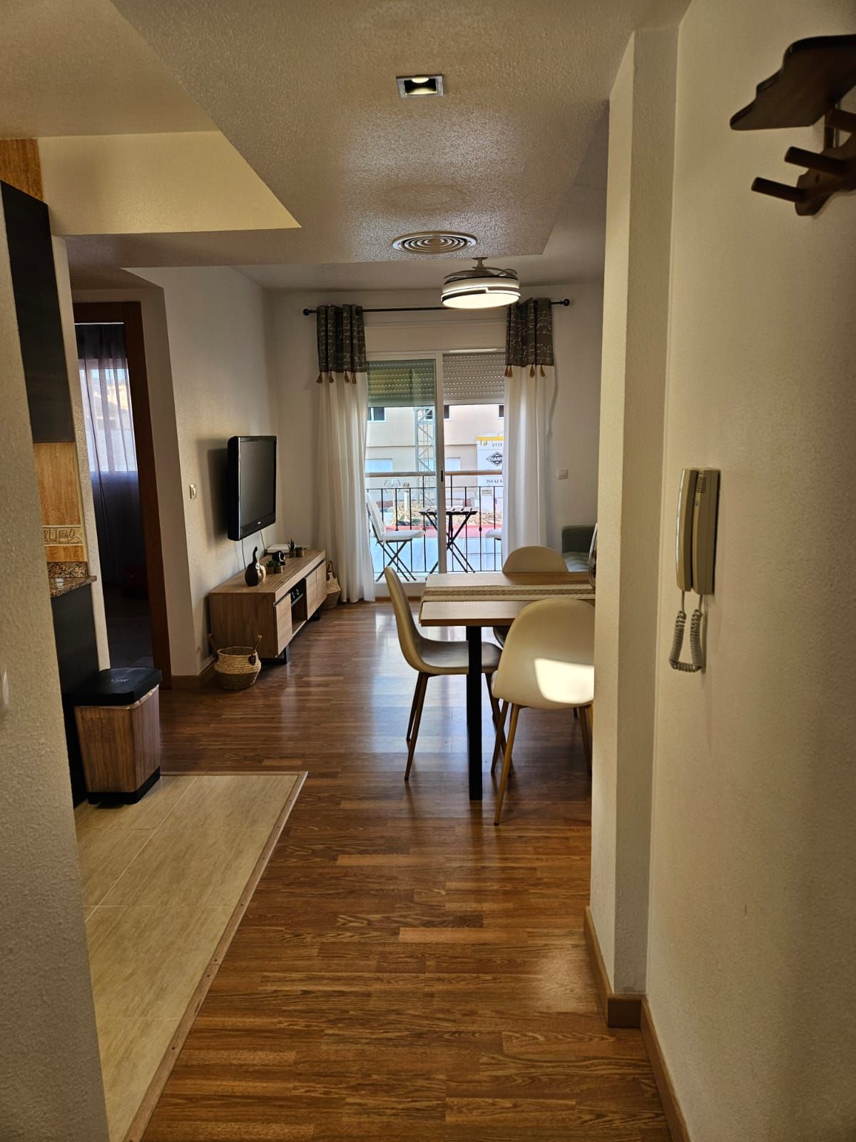 Un couloir mène à une salle à manger équipée d’une table et de chaises, d’un téléviseur et d’un téléphone.