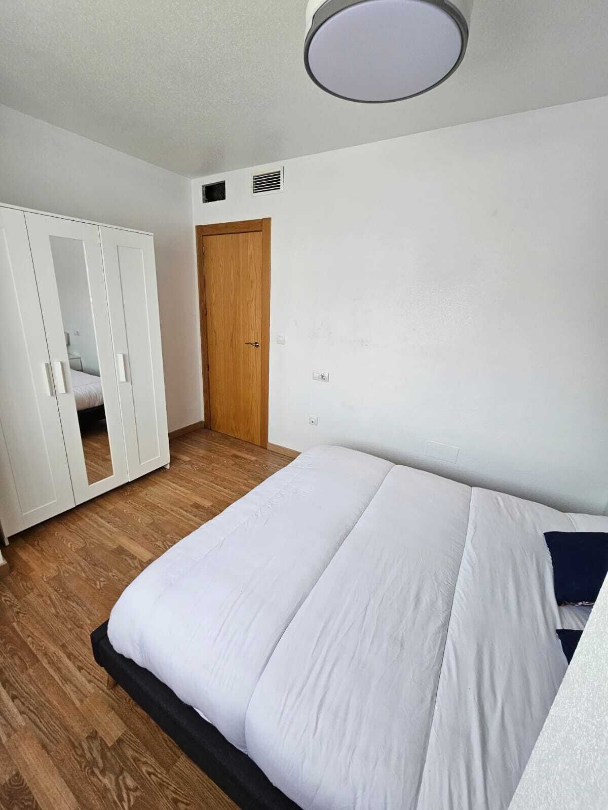 Ein Schlafzimmer mit einem Bett, einem Holzschrank und einer Tür.