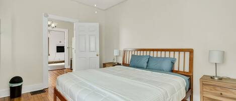 A bedroom with a wooden bed, a nightstand, a lamp, and a ceiling fan.