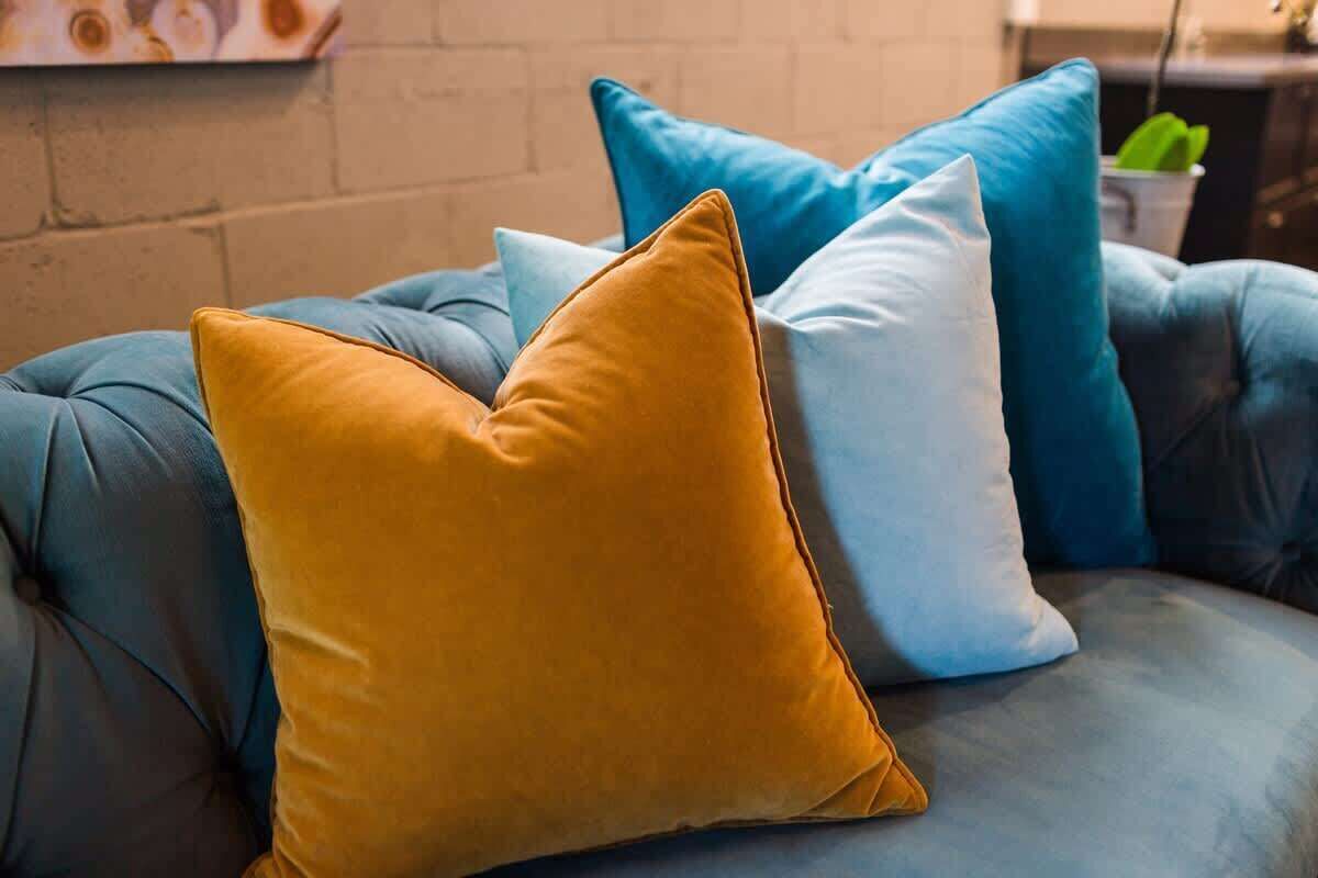 A blue sofa with three cushions in different colors.