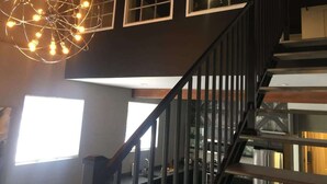Un escalier avec une rampe noire menant à un palier doté de fenêtres.