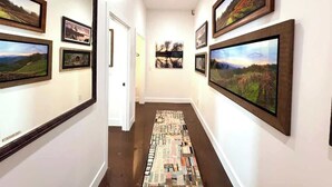 A hallway with framed landscape paintings on the walls and a patterned rug on the floor.