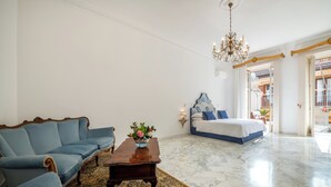 Una habitación con un sofá azul, una mesa de centro de madera con un florero, una cama con ropa de cama azul y un candelabro.