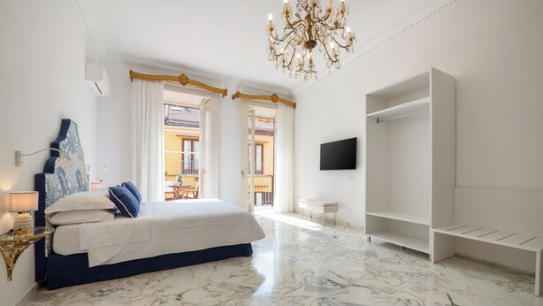 Un dormitorio con cama, televisor, armario y candelabro.
