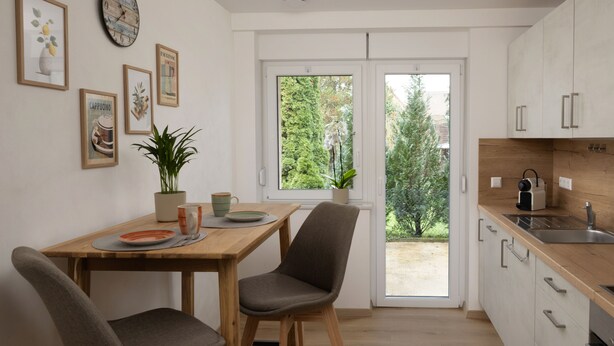 Una cocina moderna con armarios blancos, encimera de madera y un comedor con dos sillas y una mesa.