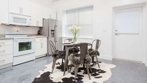 Una cucina moderna con mobili bianchi, un tavolo da pranzo con sedie e un tappeto in pelle di vacca.